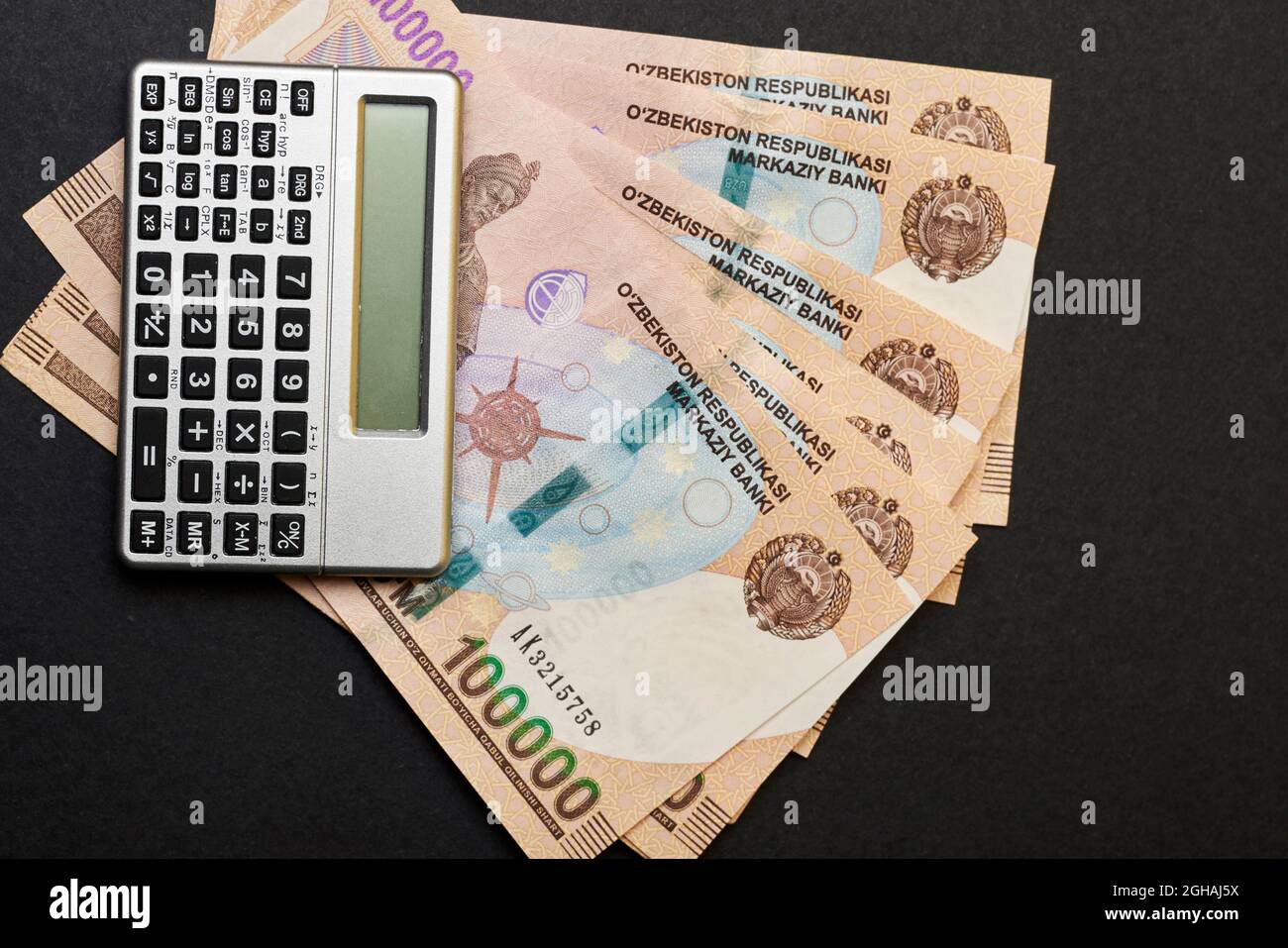 Uzbek money and calculator on black. Pile of Uzbek sums and calculator.  Concept of exchange rate. Economic or financial concept Stock Photo - Alamy