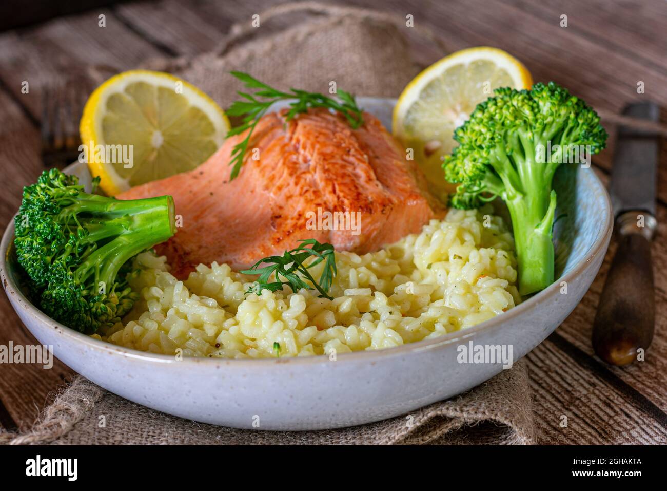 Fitness meal with salmon fillet, light risotto and broccoli isolated on wooden table. Closeup, front view Stock Photo