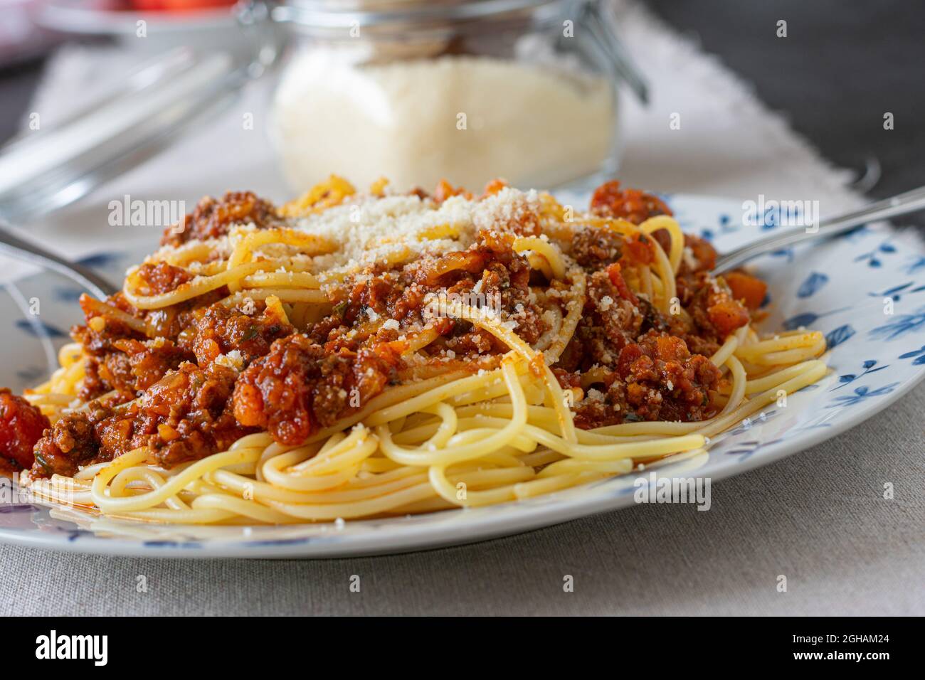 Spaghetti Bolognese with parmesan cheese on kitchen table background. Closeup and front view. Bright image Stock Photo