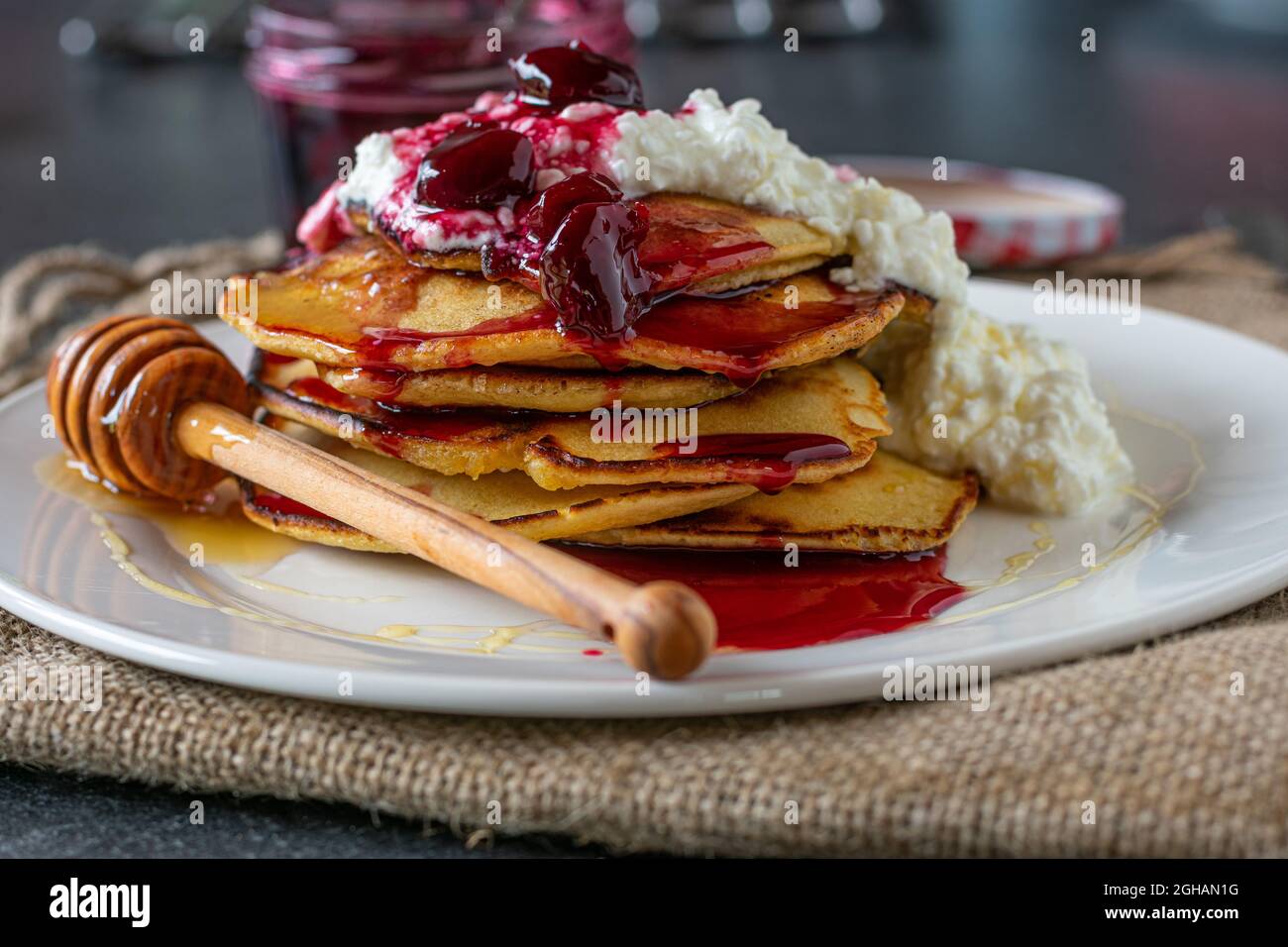 Breakfast for athletes with spelt pancakes topped with cottage cheese , cherries and honey Stock Photo