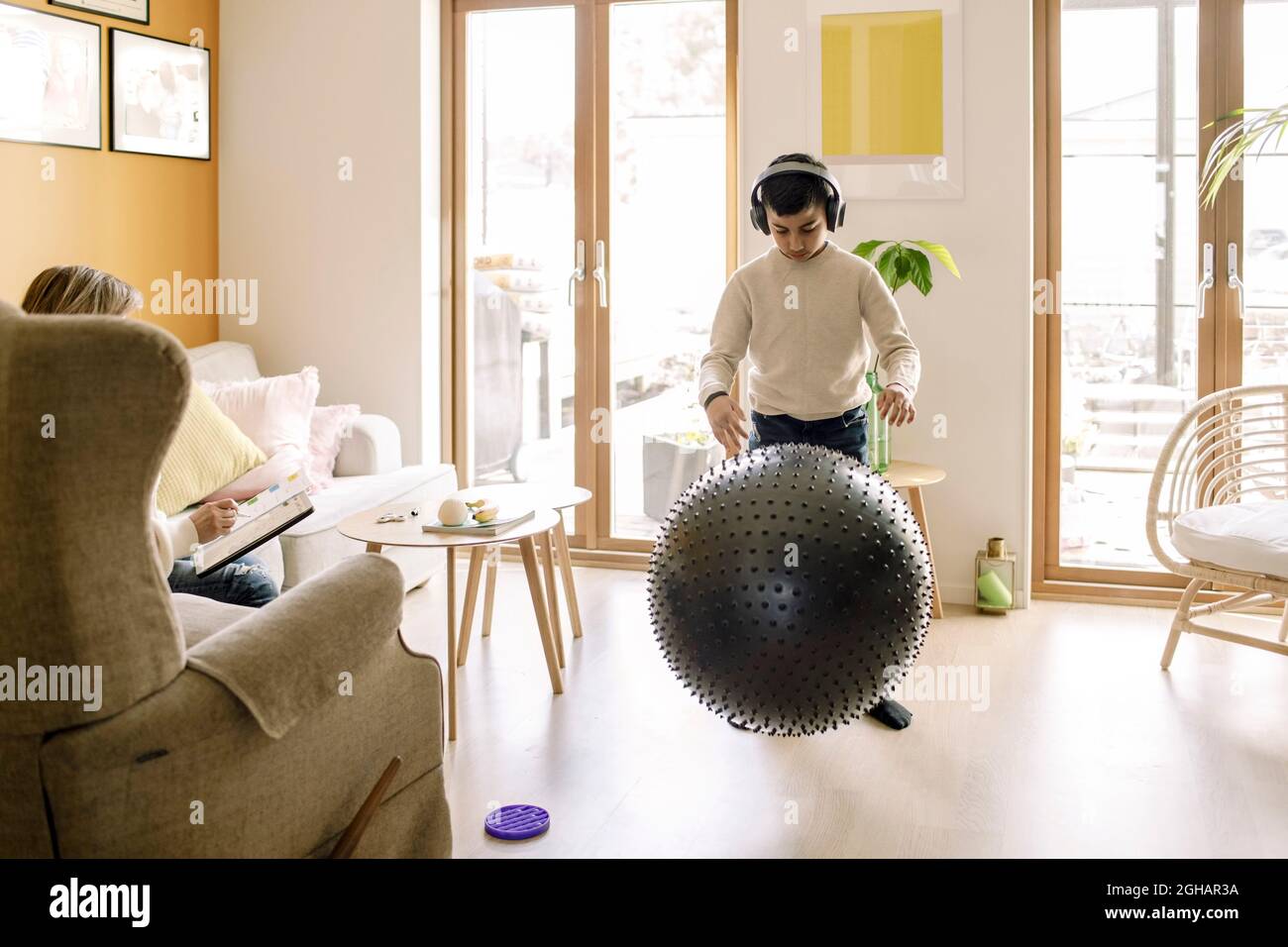 Pre-adolescent boy playing with fitness ball in living room Stock Photo