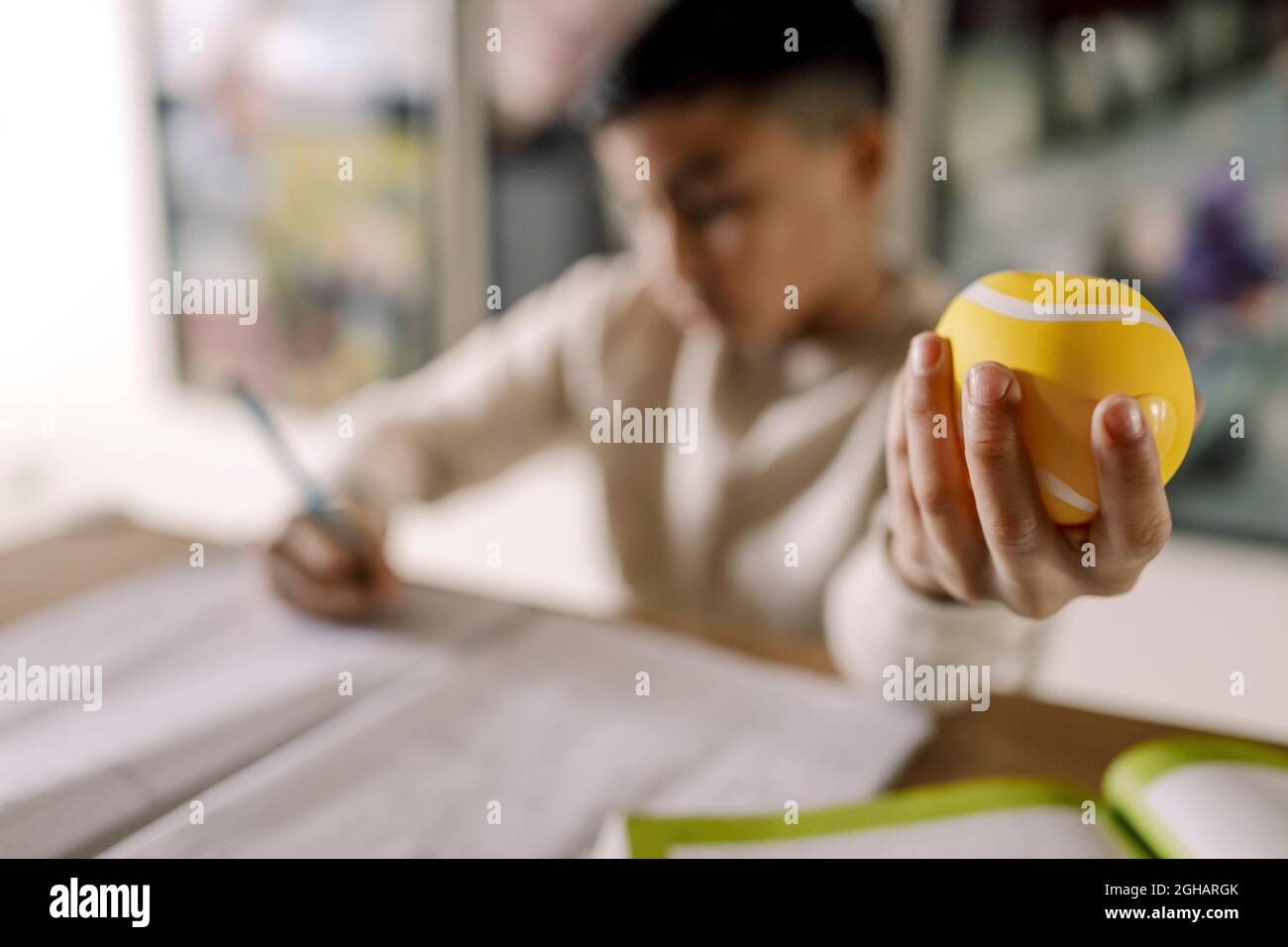 Boy holding stress ball while learning in living room Stock Photo
