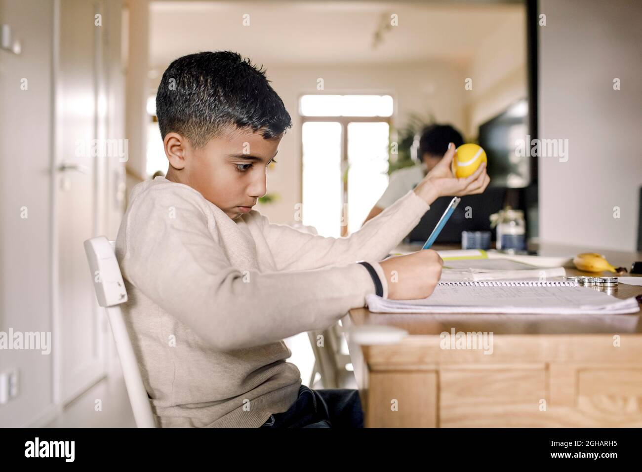 Boy learning while writing in book at home Stock Photo - Alamy