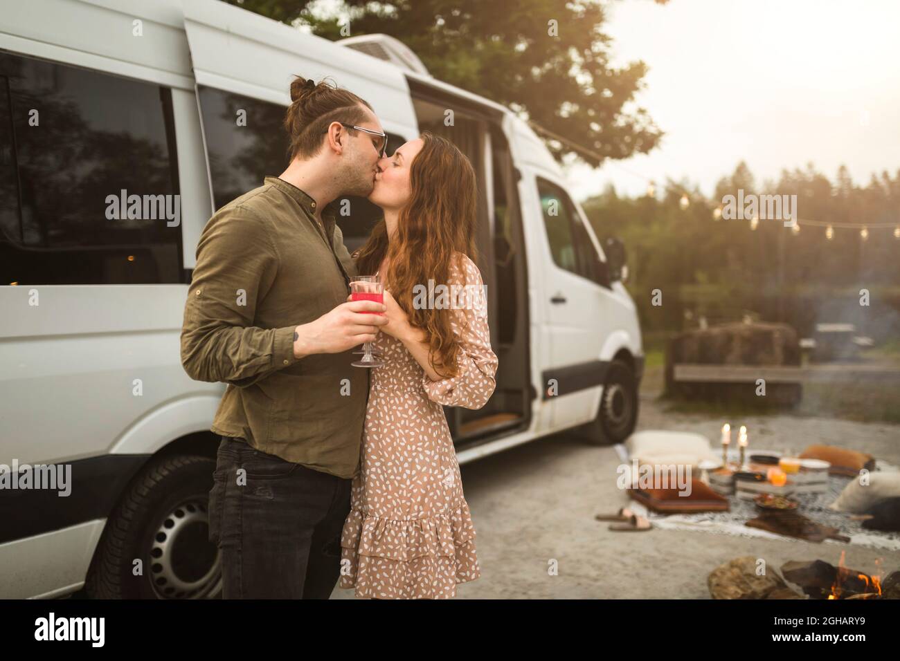 Heterosexual couple kissing by motor home during vacation Stock Photo