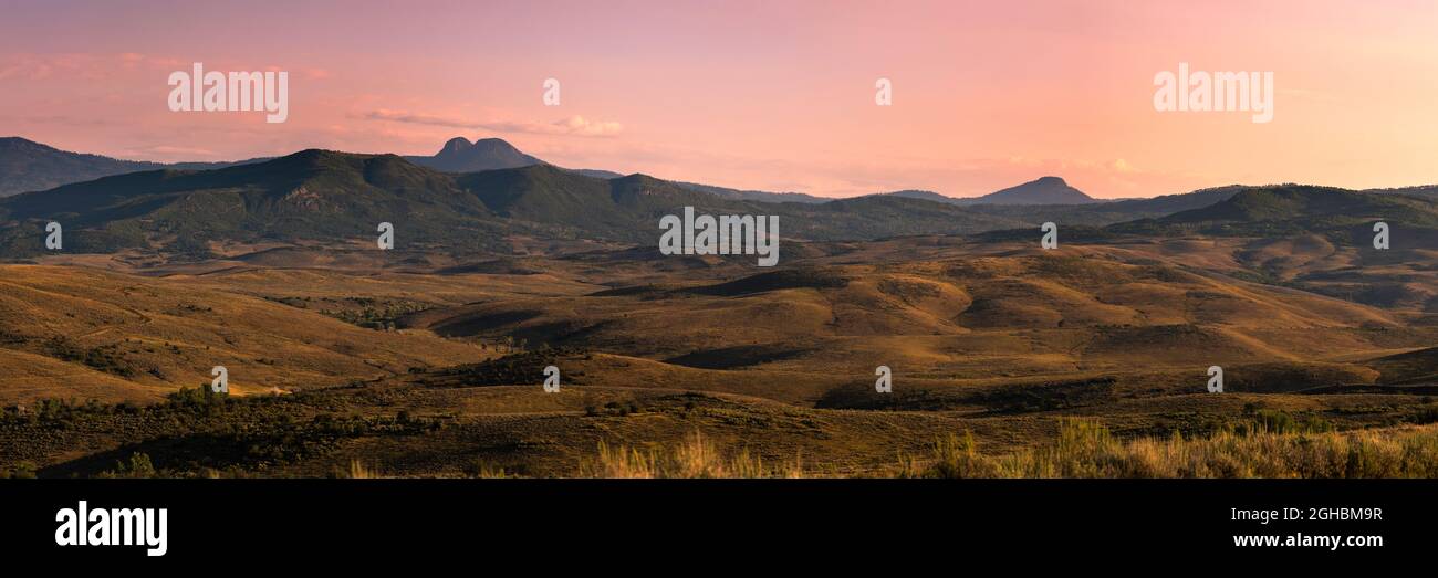 An hour after sunrise on a large meadow north of Hayden, Colorado.  The sky has warm pink tones and the landscape has lots of greens yellows, and blue Stock Photo