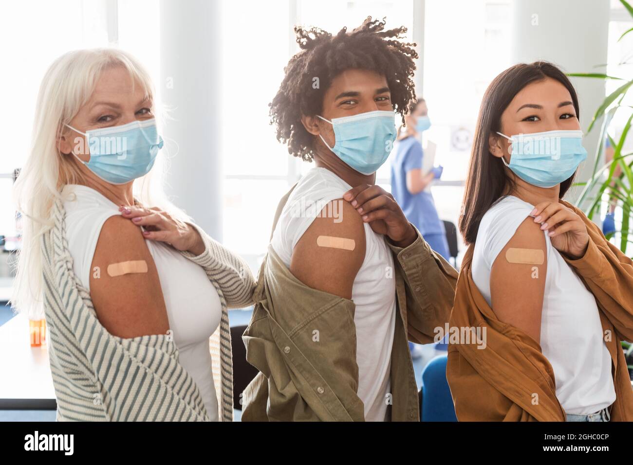 Diverse Group Showing Vaccinated Arm With Adhesive Bandage In Clinic Stock Photo