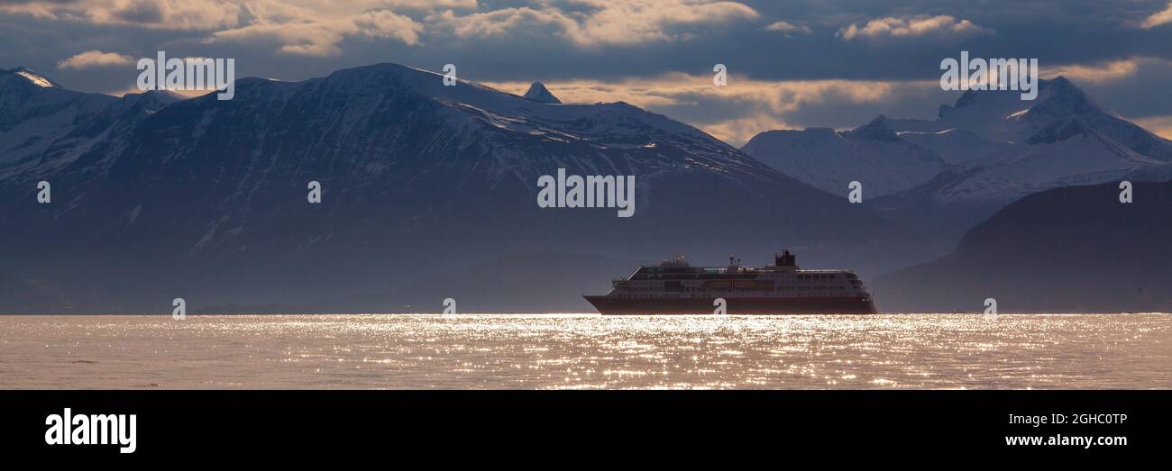 Beautiful seascape of Norway with cruise in the fjord. Colorful sky and mountains in background. Stock Photo