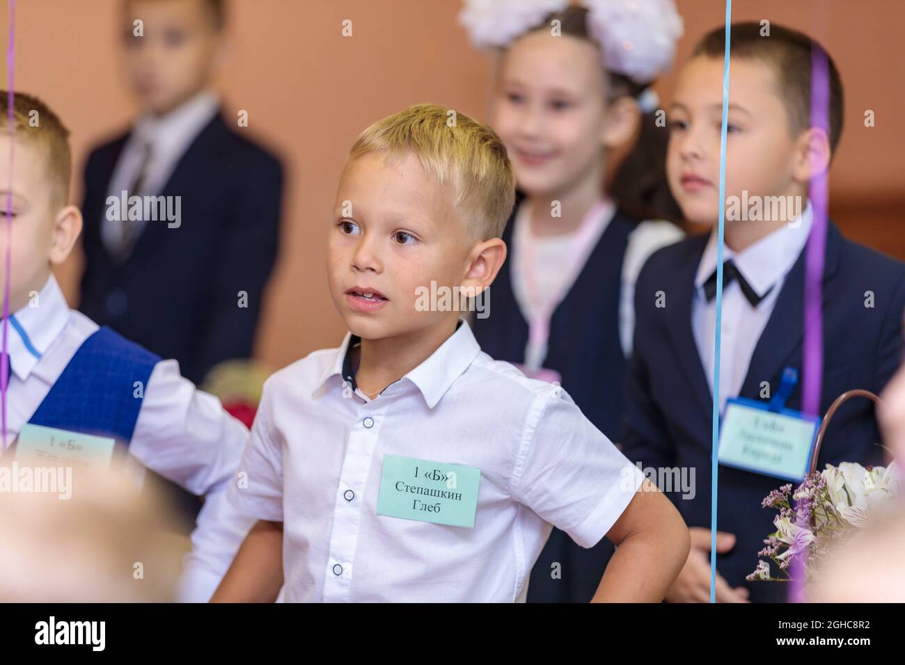 First graders in the classroom perform a warm-up while standing. She is in grade 1 school. Moscow, Russia, September 1, 2021 Stock Photo