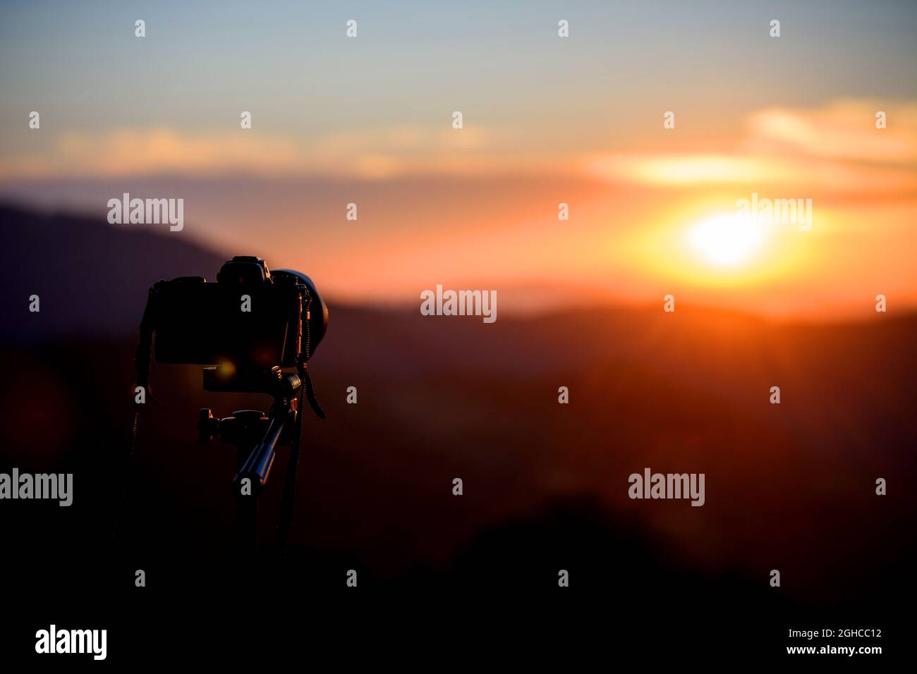 Camera on tripod and photography view with blurred focus mountain landscape. Sunset or sunrise light Stock Photo