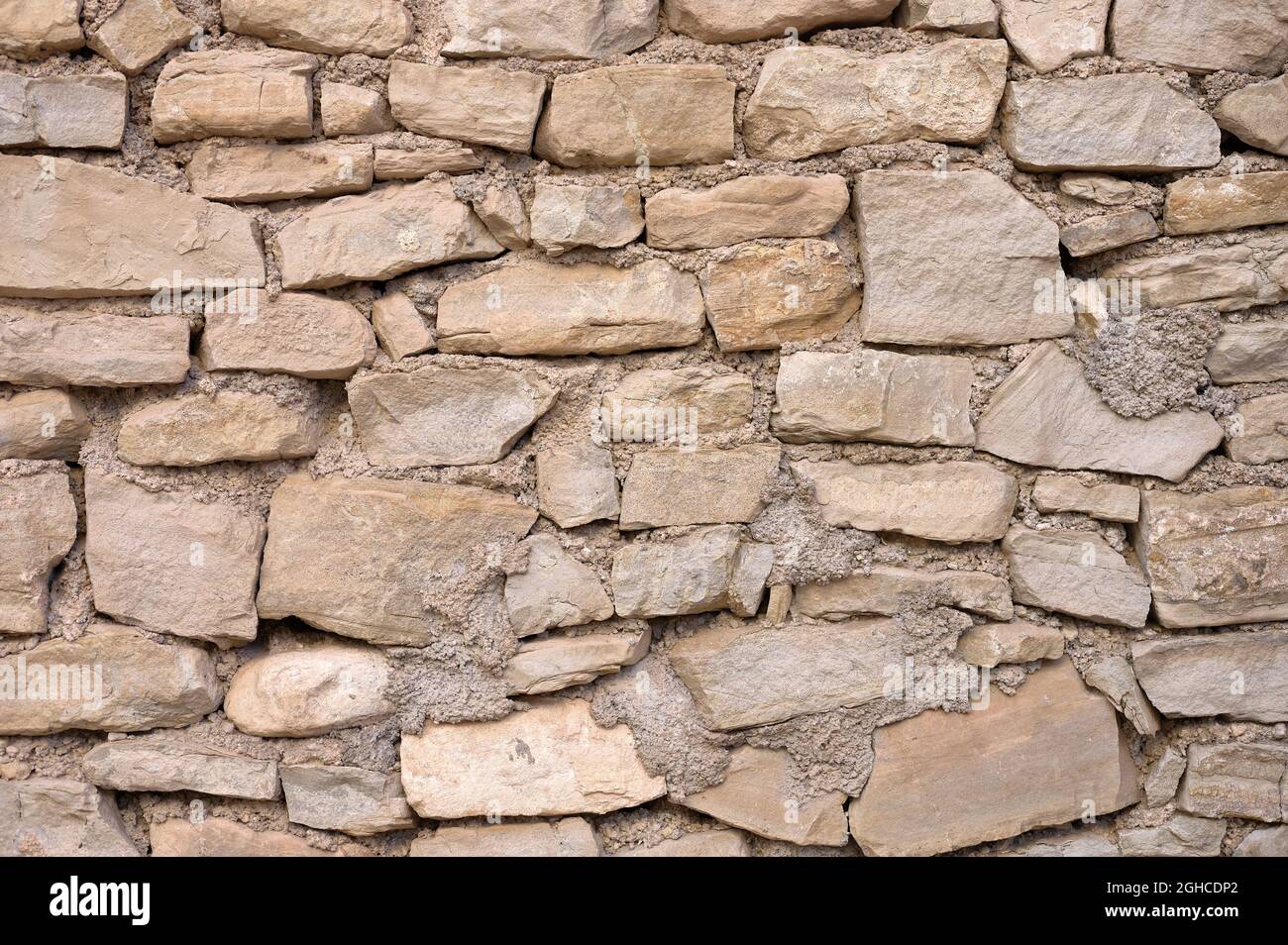 detail of an old irregular stone wall with mortar Stock Photo