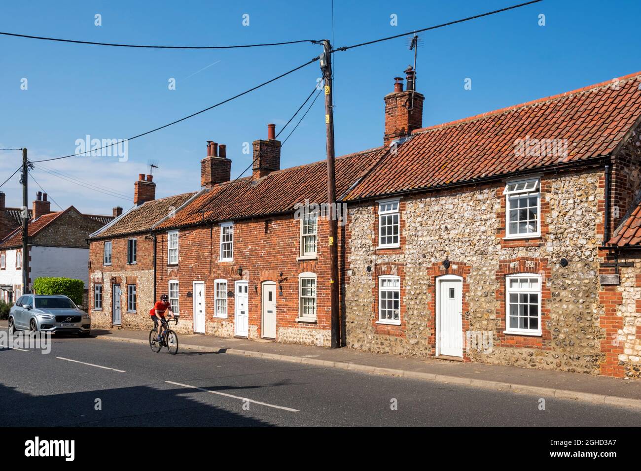 A cyclist passing cottages on the A149 road through Thornham on the North Norfolk coast. Stock Photo