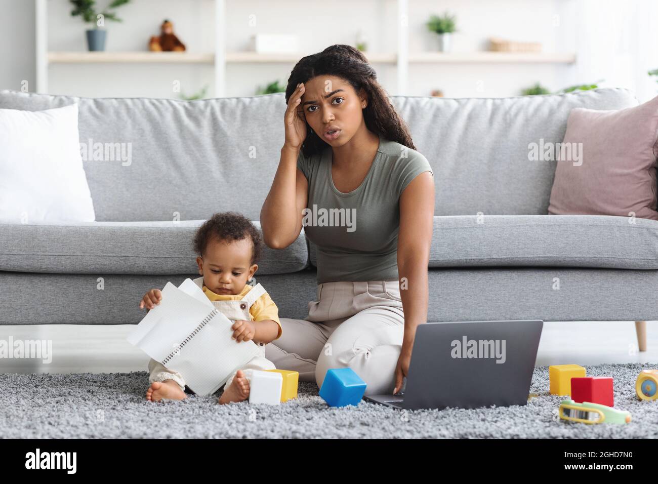 Stressed Black Mother Trying To Work At Home While Baby Distracting Her Stock Photo