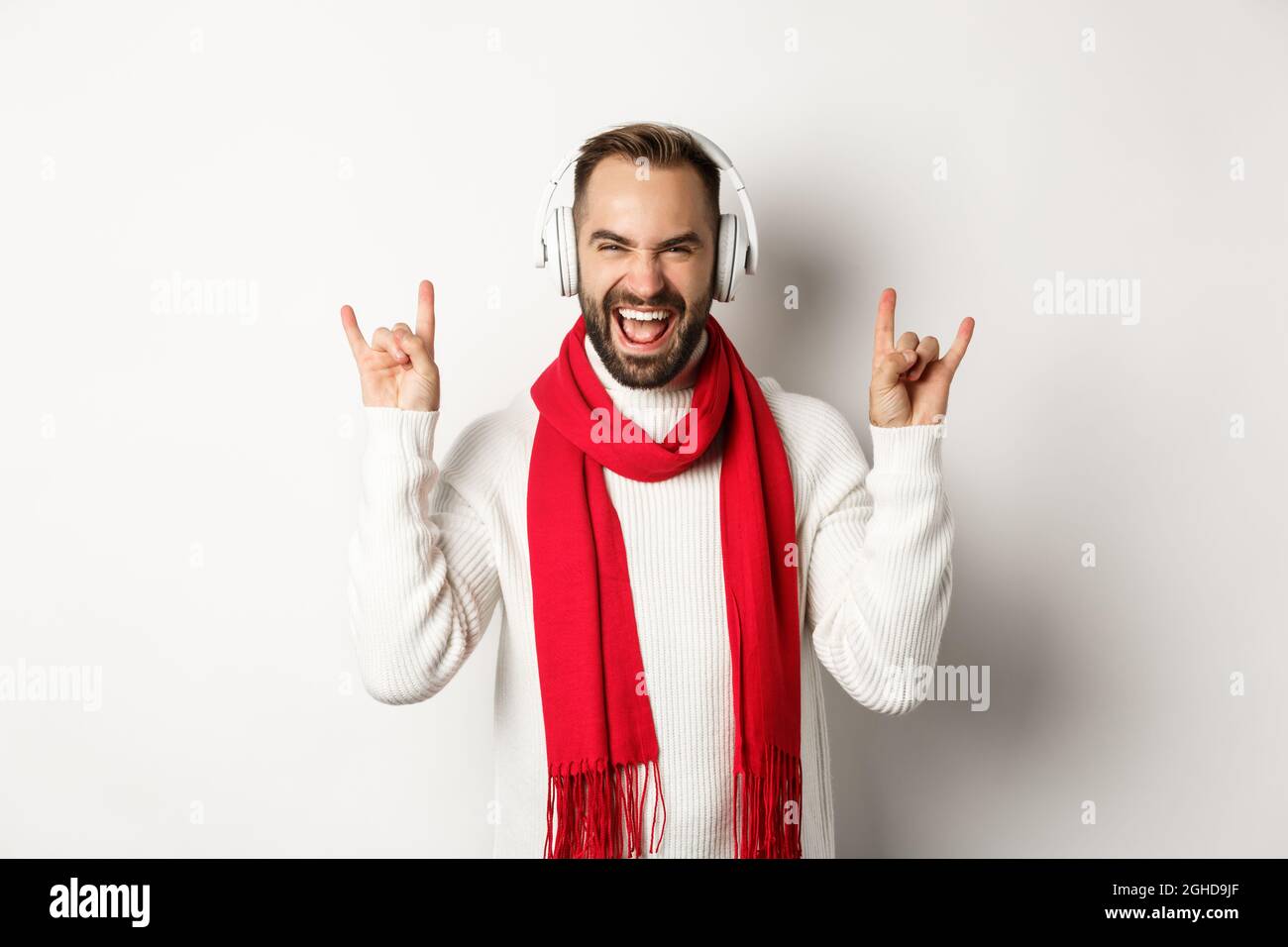 Joven escuchando heavy metal con auriculares, mostrando gesto rockero y expresión de alegría