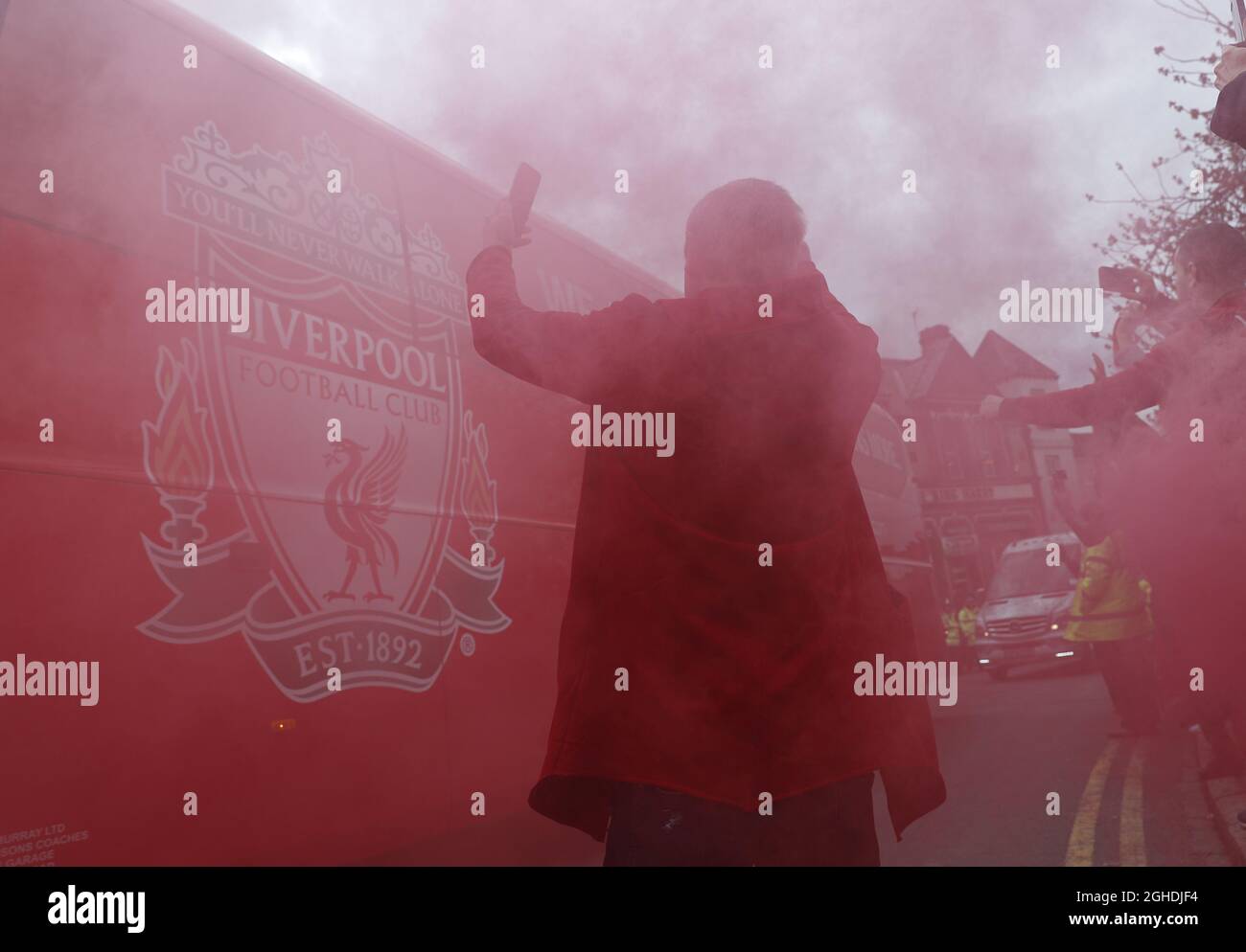 A fan tries to take pictures as red smoke from flares swirls around the team coach before  the Premier League match at Anfield, Liverpool. Picture date: 31st March 2019. Picture credit should read: Darren Staples/Sportimage via PA Images Stock Photo