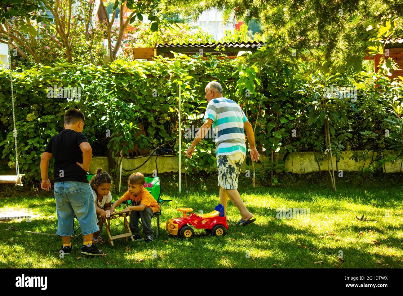 Grandfather with his grandchildren in the garden. Happy family enjoying time together Stock Photo