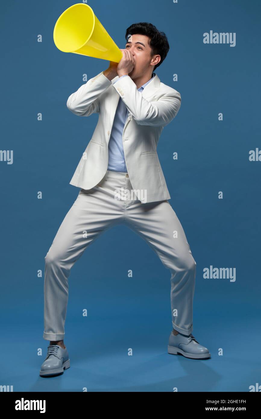 Studio shot of young man shouting through megaphone Stock Photo