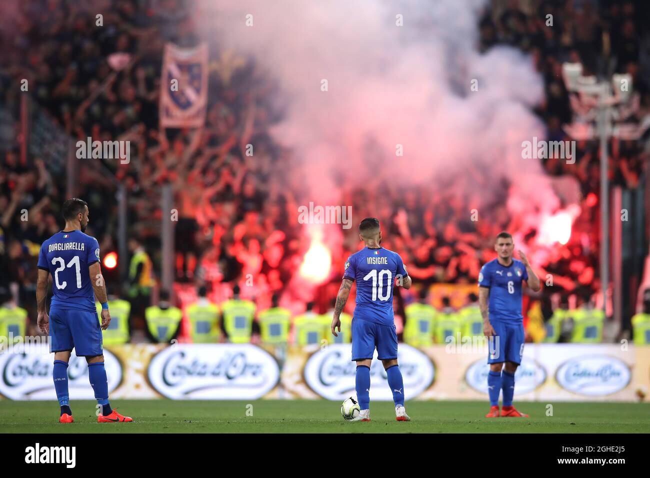 Fabio Quagliarella and Lorenzo Insigne of Italy wait to restart the match  as Marco Verratti looks on after Bosnia fans lit flares and celebrate  following Edin Dzeko's goal which gave the side