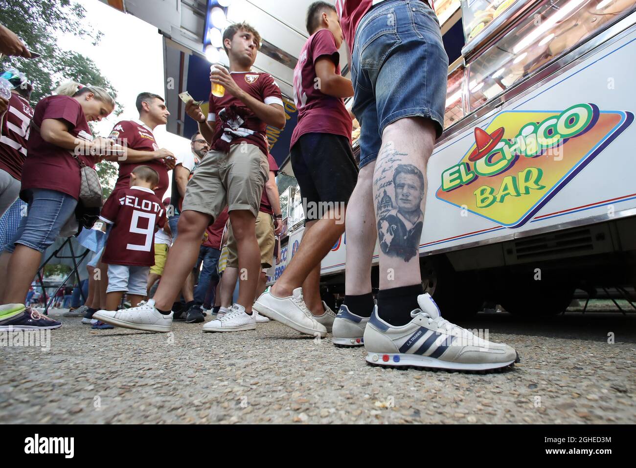 A fan's leg tattoo bearing the club crest, the Superga Basilica and a portrait of Grande Torino and Italy captain Valentino Mazzola is seen at a queue for refreshments before the Serie A match at Stadio Grande Torino, Turin. Picture date: 25th August 2019. Picture credit should read: Jonathan Moscrop/Sportimage via PA Images Stock Photo