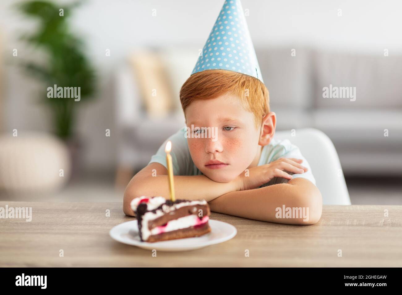 Upset birthday boy looking at lid candle on his cake Stock Photo