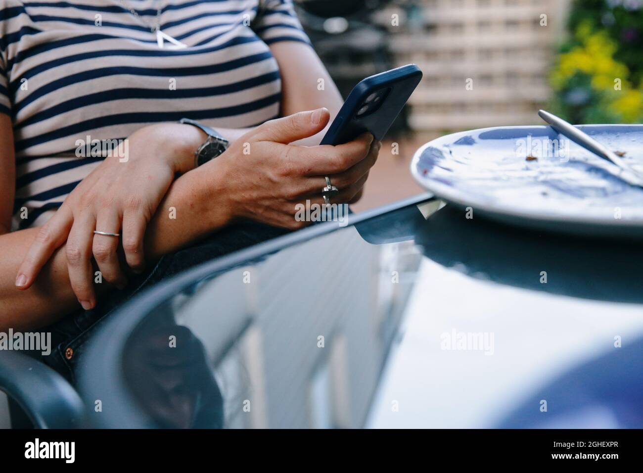 A woman checks her iphone smartphone at the dinner table outside in London, England Stock Photo