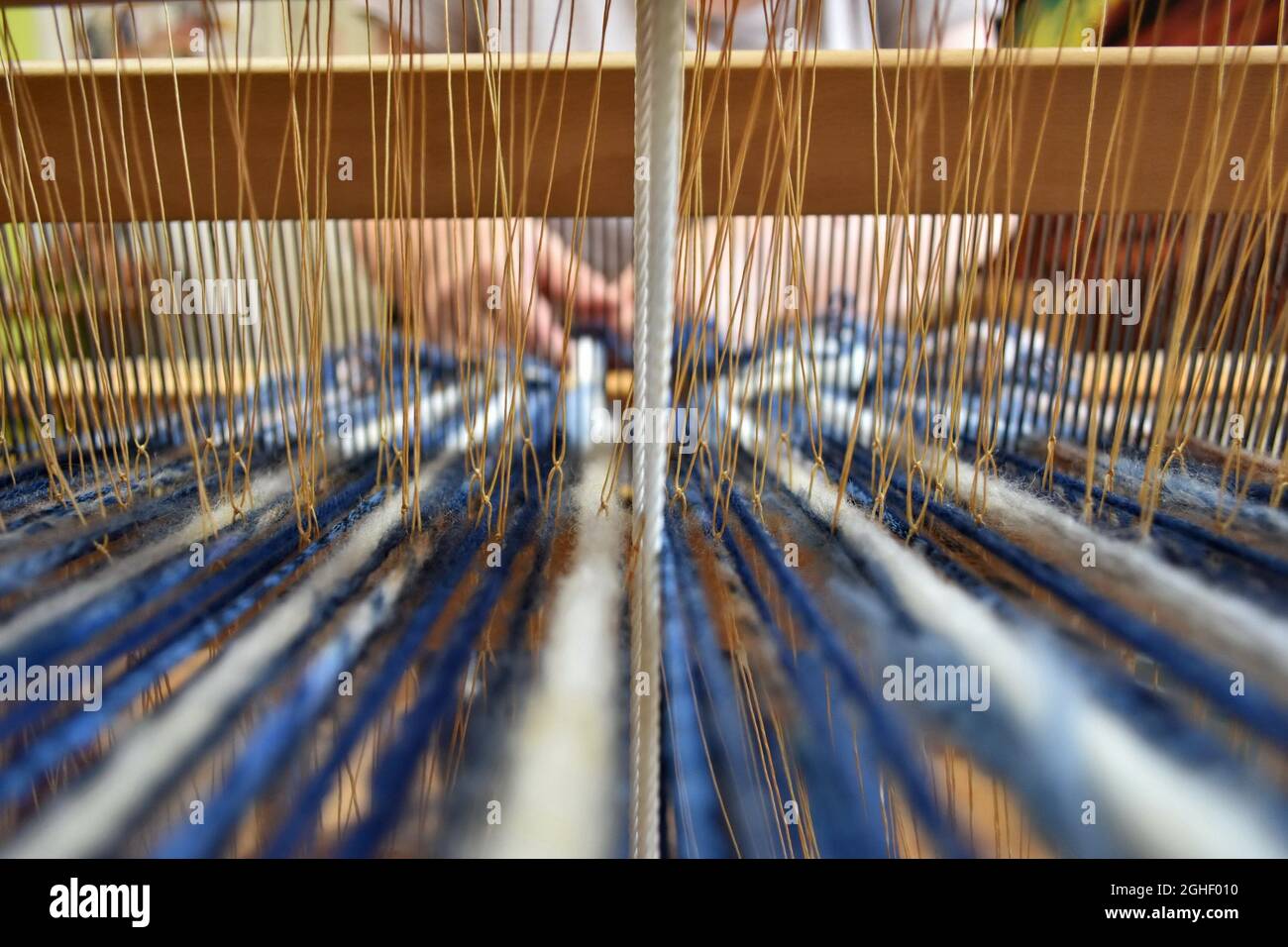 Closeup shot of a woman's hands weaving on a loom Stock Photo