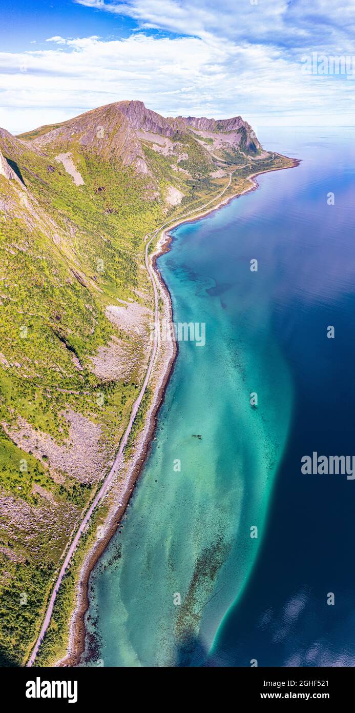 Aerial view of coastal road nearby the crystal sea at feet of Husfjellet mountain, Steinfjord, Senja, Troms county, Norway Stock Photo