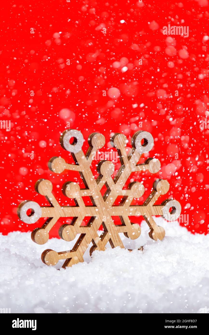 Snow on a red background, snowfall or falling snow. Large wooden snowflake in the snow. Christmas concept. New Year theme, panoramic photo for a Stock Photo