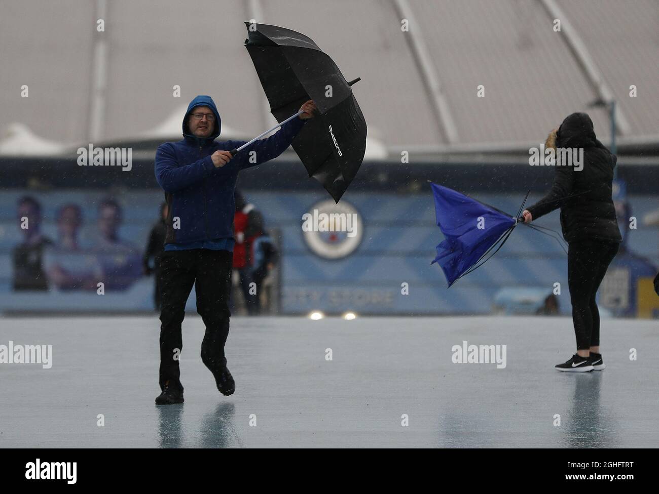Fans struggle with his umbrellas after the Premier League match between Manchester City and West Ham United was postponed because of weather conditions at the Etihad Stadium, Manchester. Picture date: 9th February 2020. Picture credit should read: Darren Staples/Sportimage via PA Images Stock Photo
