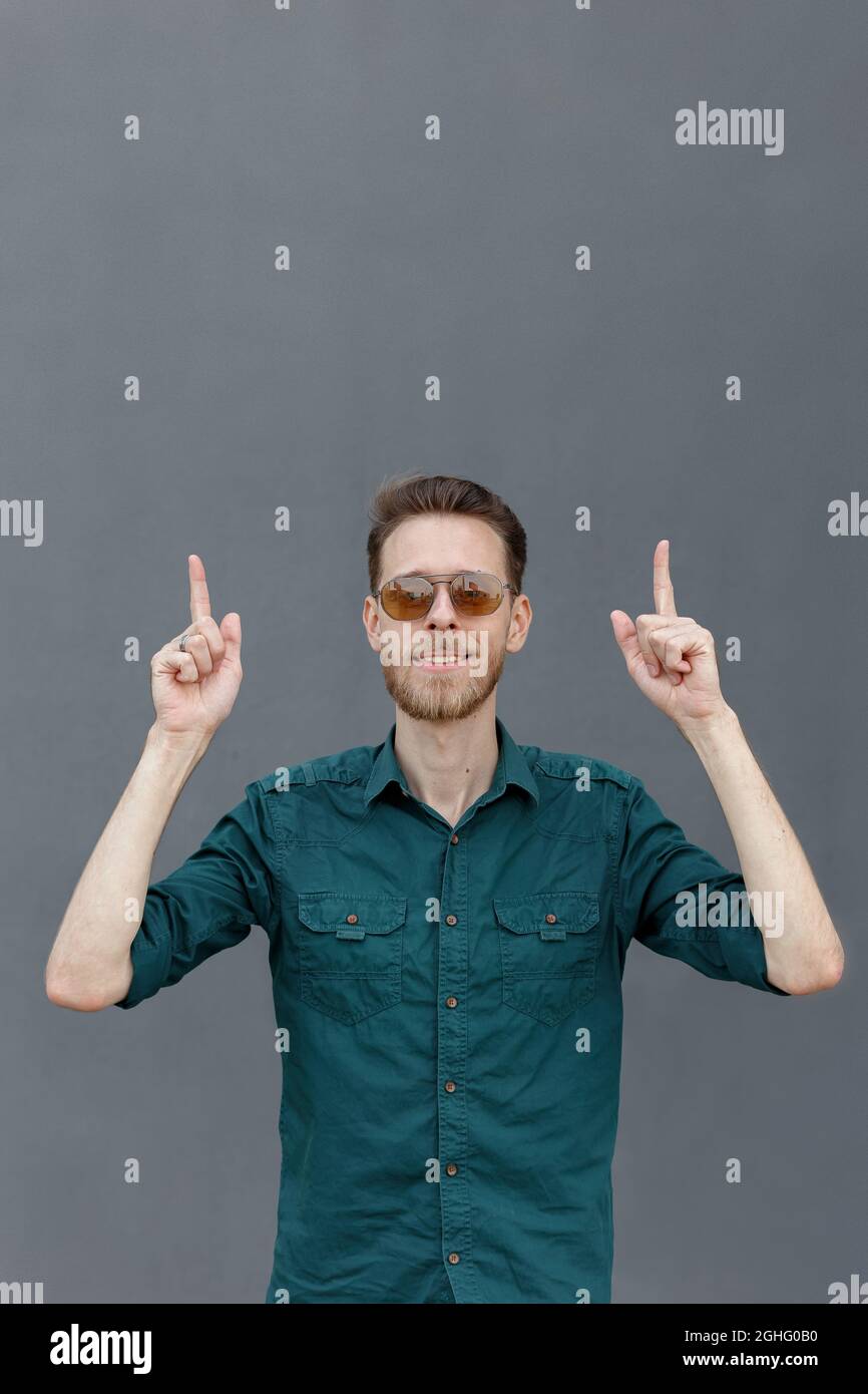 A young man in sunglasses gestures to look up, where is the place for an inscription or banner Stock Photo