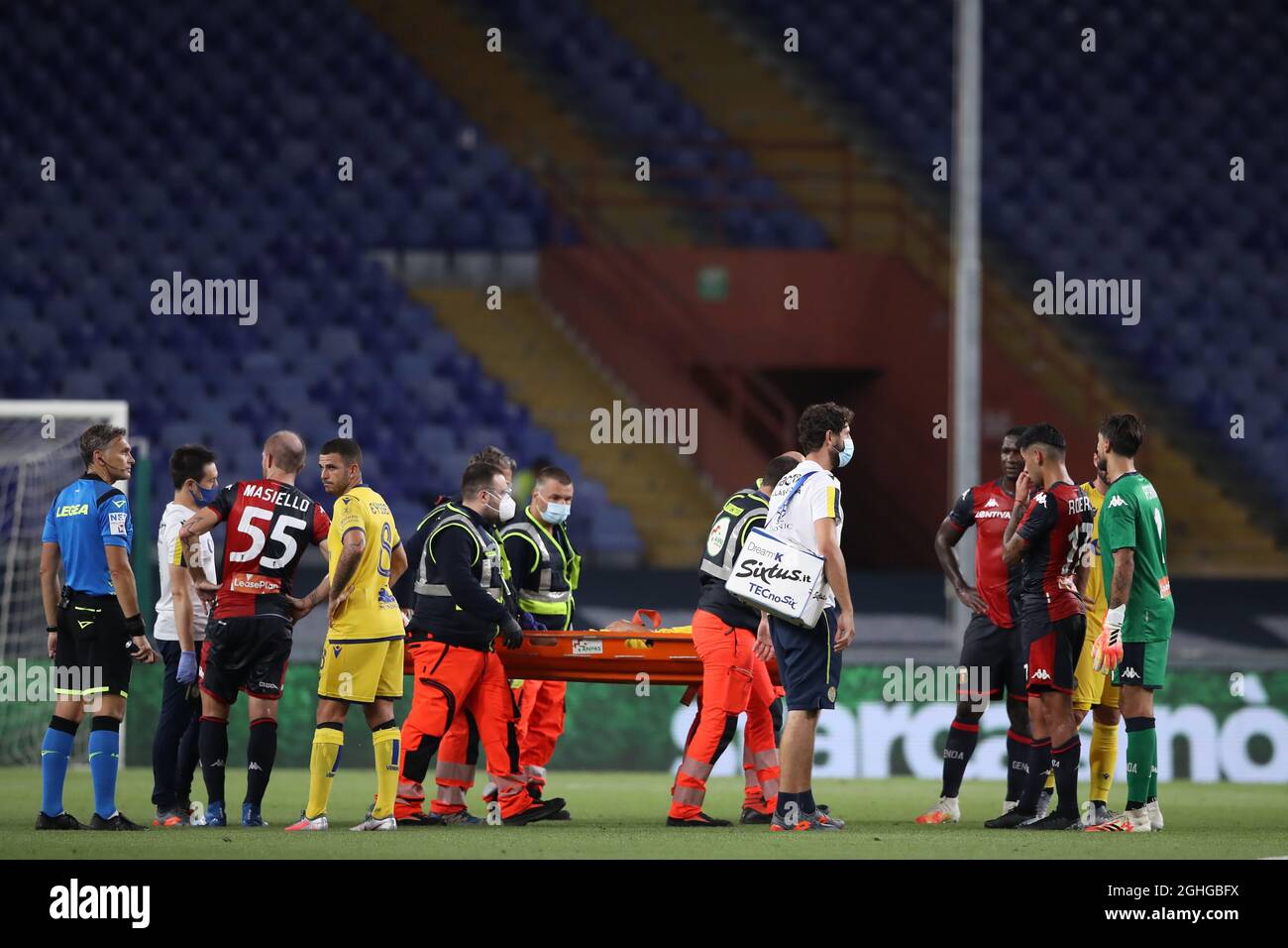 Cristian Romero of Genoa CFC looks on remorsefully as Matteo Pessina of Hellas Verona is carried away on a stretcher by medics after dislocating his patella in a challenge between the two which earn the Genoa CFC defender a yellow card during the Serie A match at Luigi Ferraris, Genoa. Picture date: 2nd August 2020. Picture credit should read: Jonathan Moscrop/Sportimage via PA Images Stock Photo