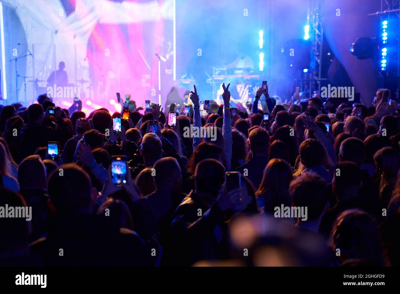 crowd of people in club. lot of people at the concert. silhouettes of people on background of stage Stock Photo