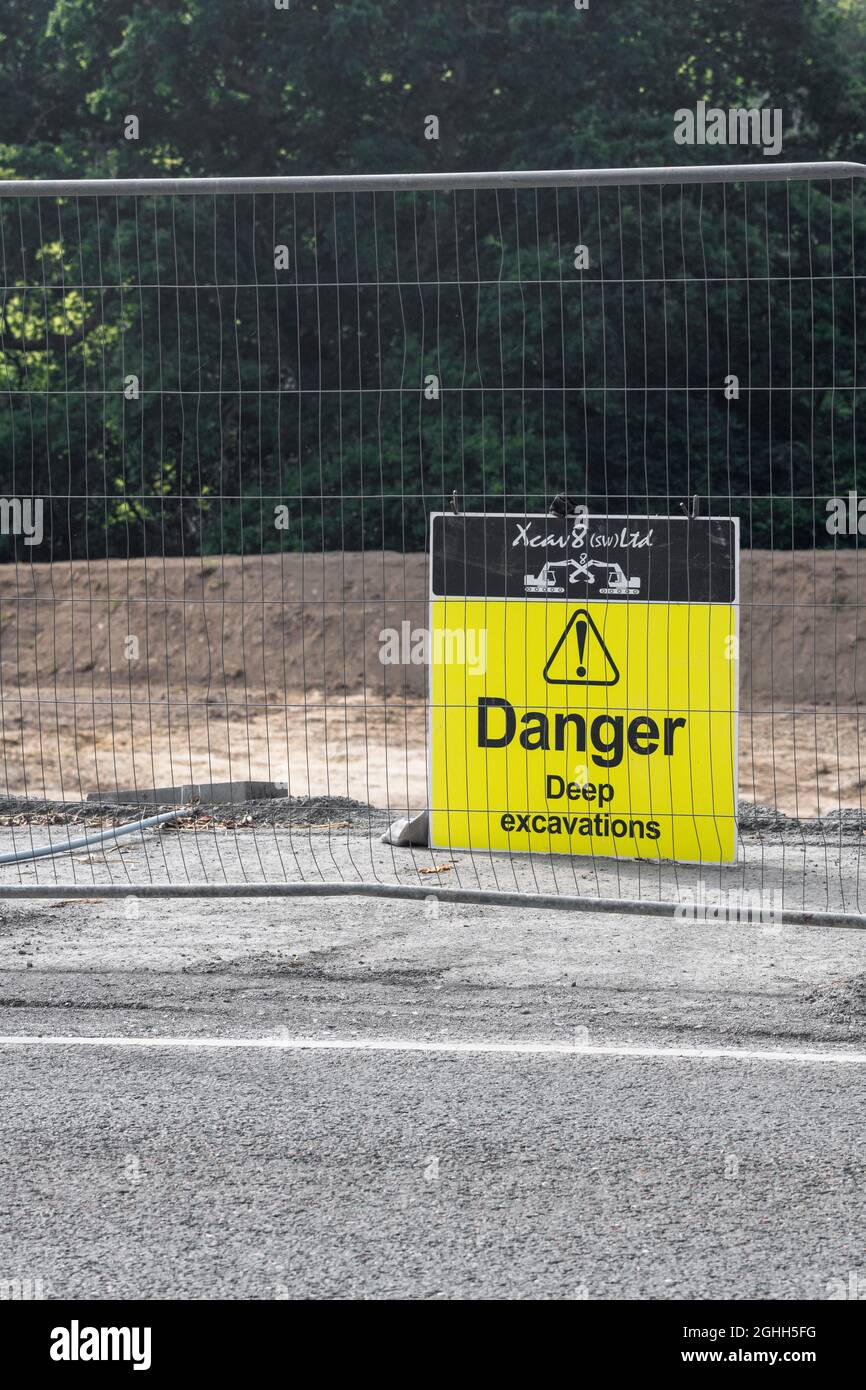 Plant hire company's yellow warning sign, with formal yellow triangle, warning of deep excavations at a construction site. For Health & Safety regs UK Stock Photo