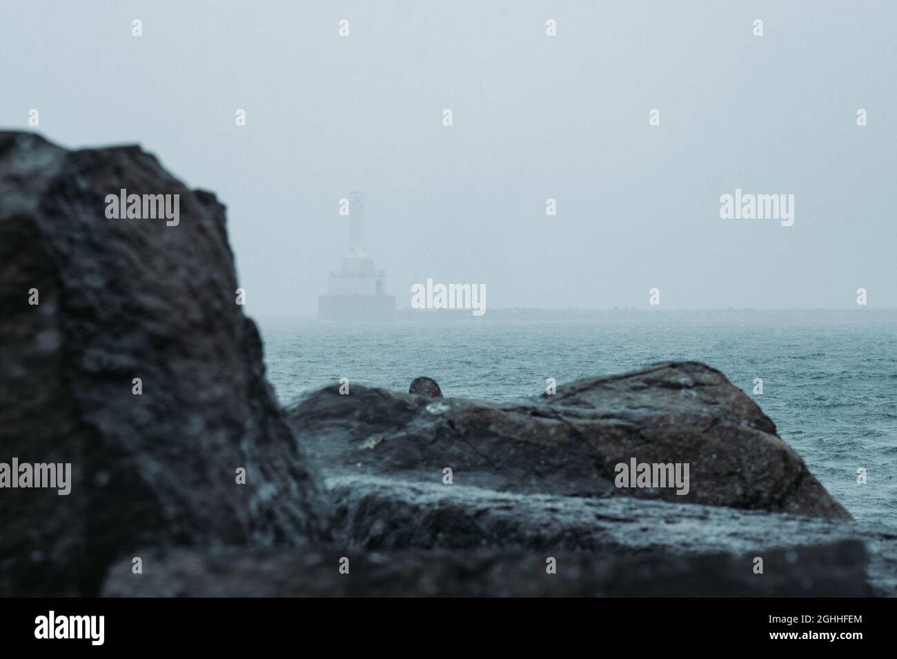 Boat in the foggy sea approaching a rocky shore Stock Photo - Alamy