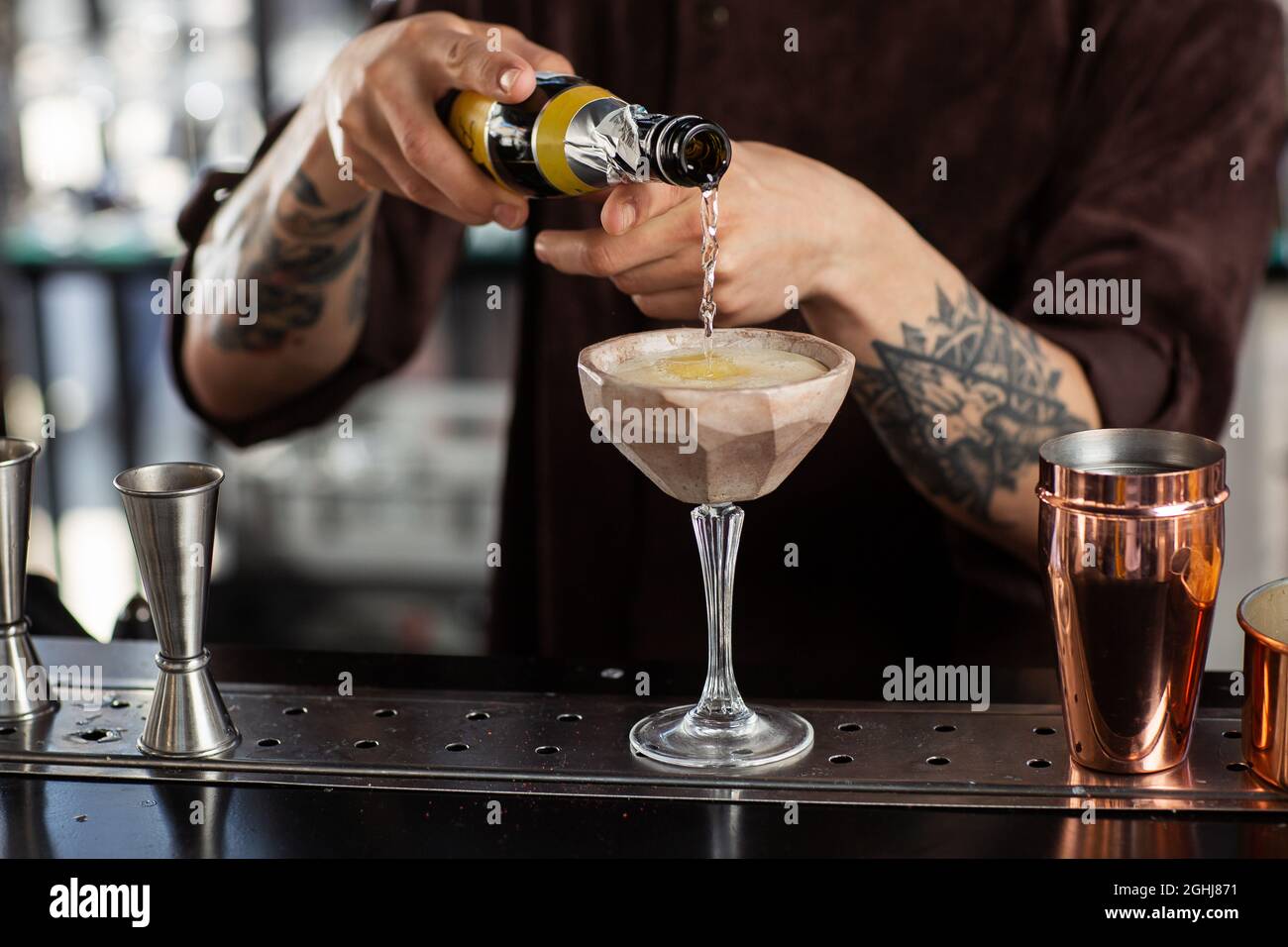https://c8.alamy.com/comp/2GHJ871/male-bartender-pouring-to-the-measuring-glass-cup-with-ice-cubes-an-alcoholic-drink-from-steel-jigger-on-the-bar-counter-on-the-blurred-background-2GHJ871.jpg