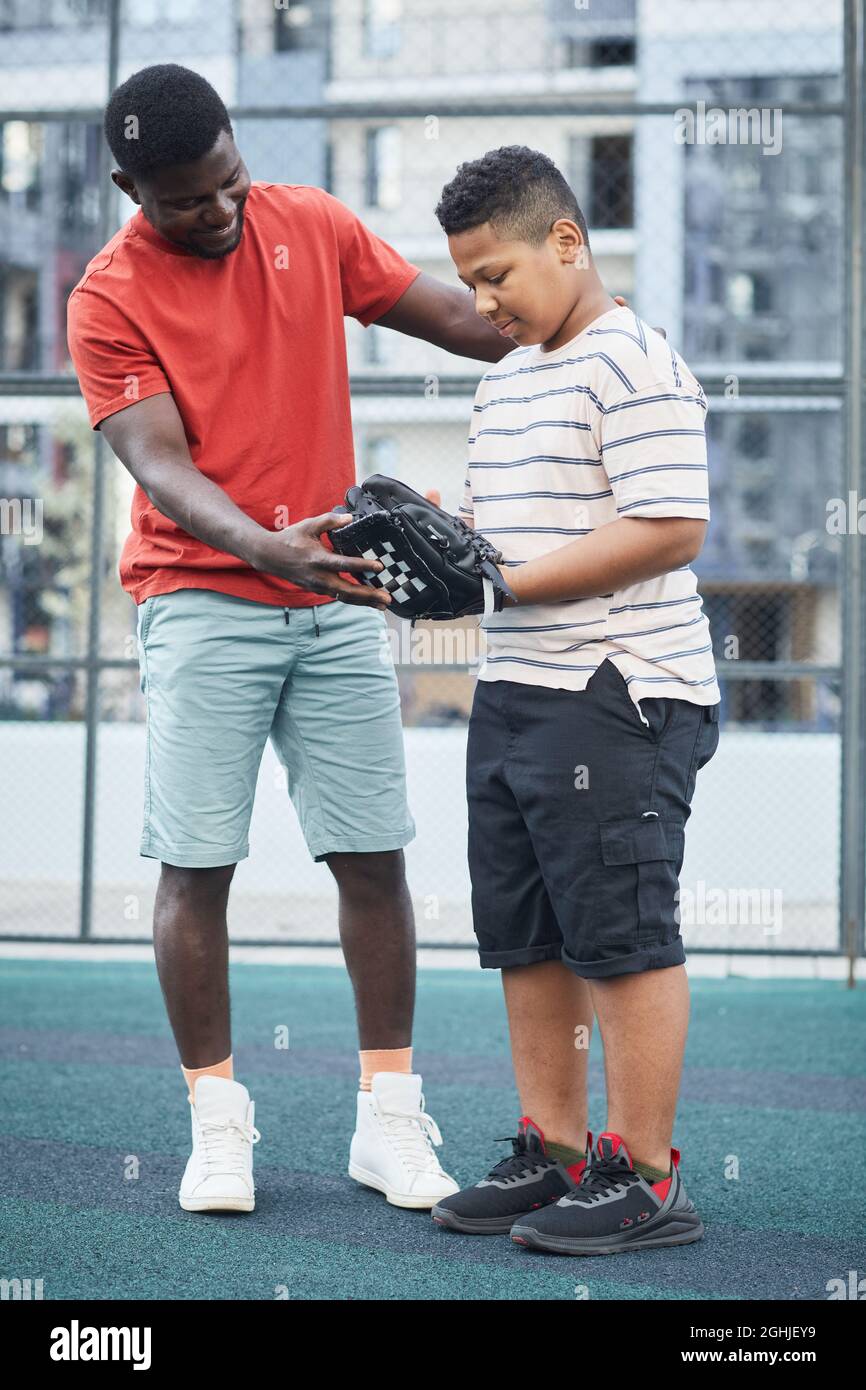 Positive AfricanAmerican father in red tshirt showing how to catch