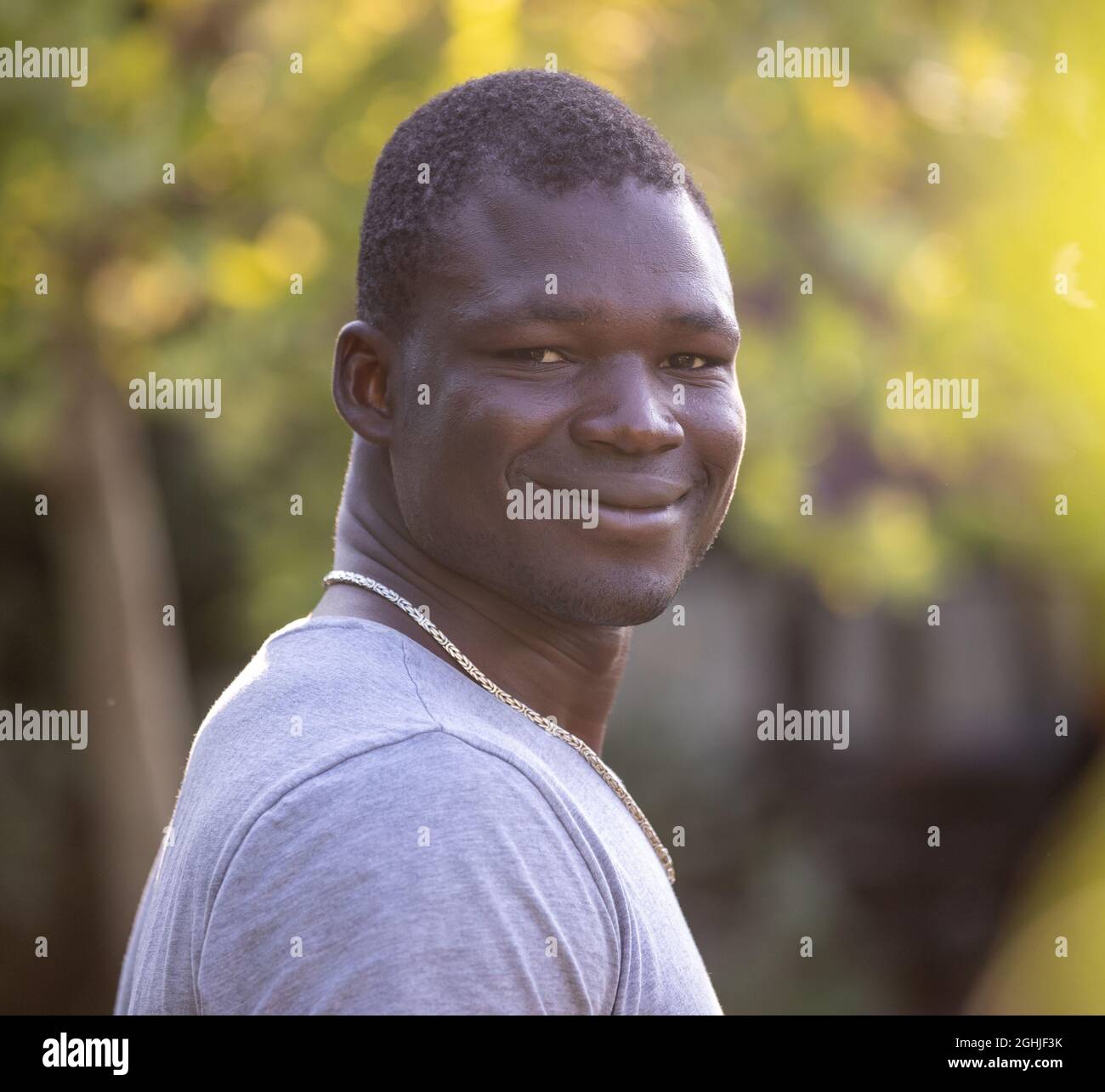 Portrait of smiling and satisfied young african man standing in park ...