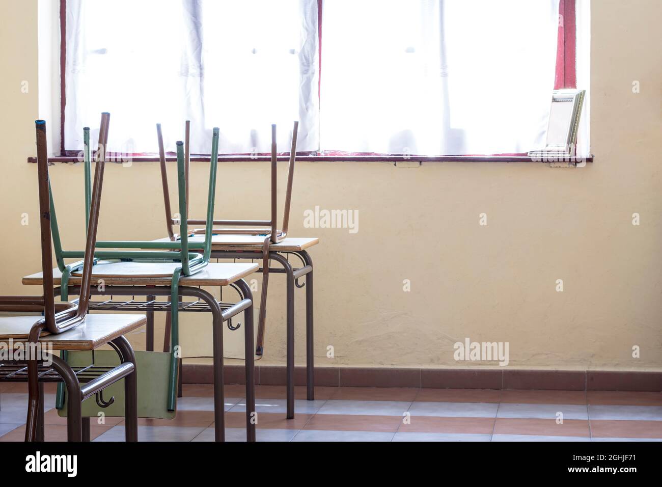 Infant school chairs on top of the tables.The photograph is taken in horizontal format. Stock Photo