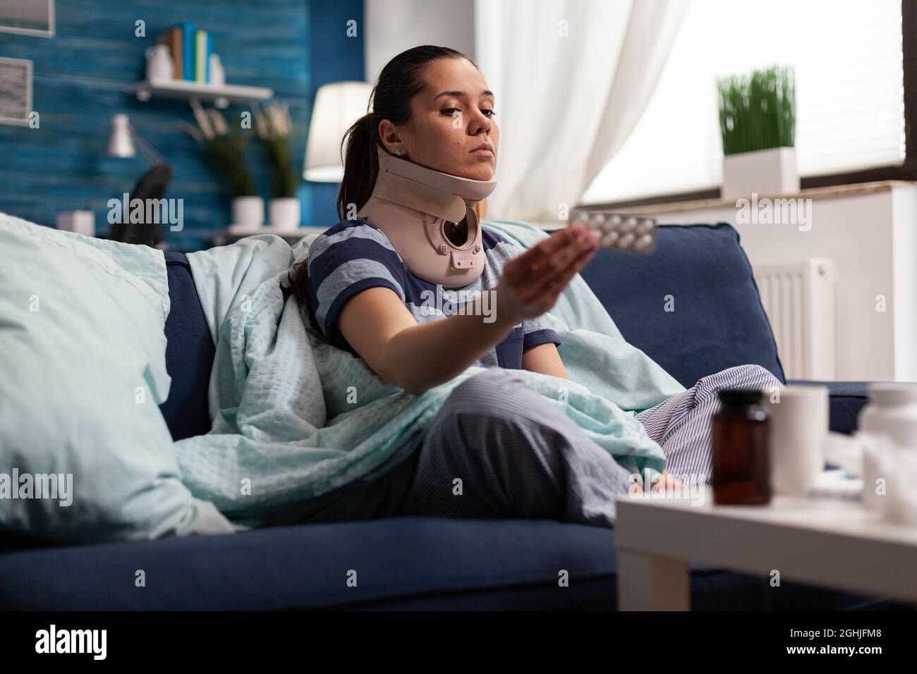 Woman in neck brace suffering from pain on sofa after bad accident