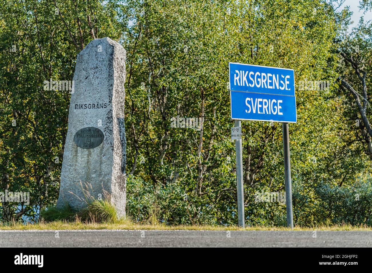 State border between Norway and Sweden in Northern Sweden, mountains in Lappland. Mile stone with Swedish text and blue road sign with Norwegian words Stock Photo