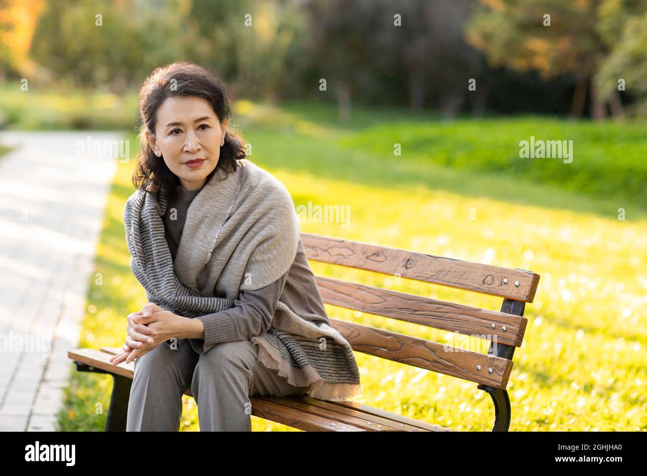 Senior woman sitting on park bench Stock Photo - Alamy