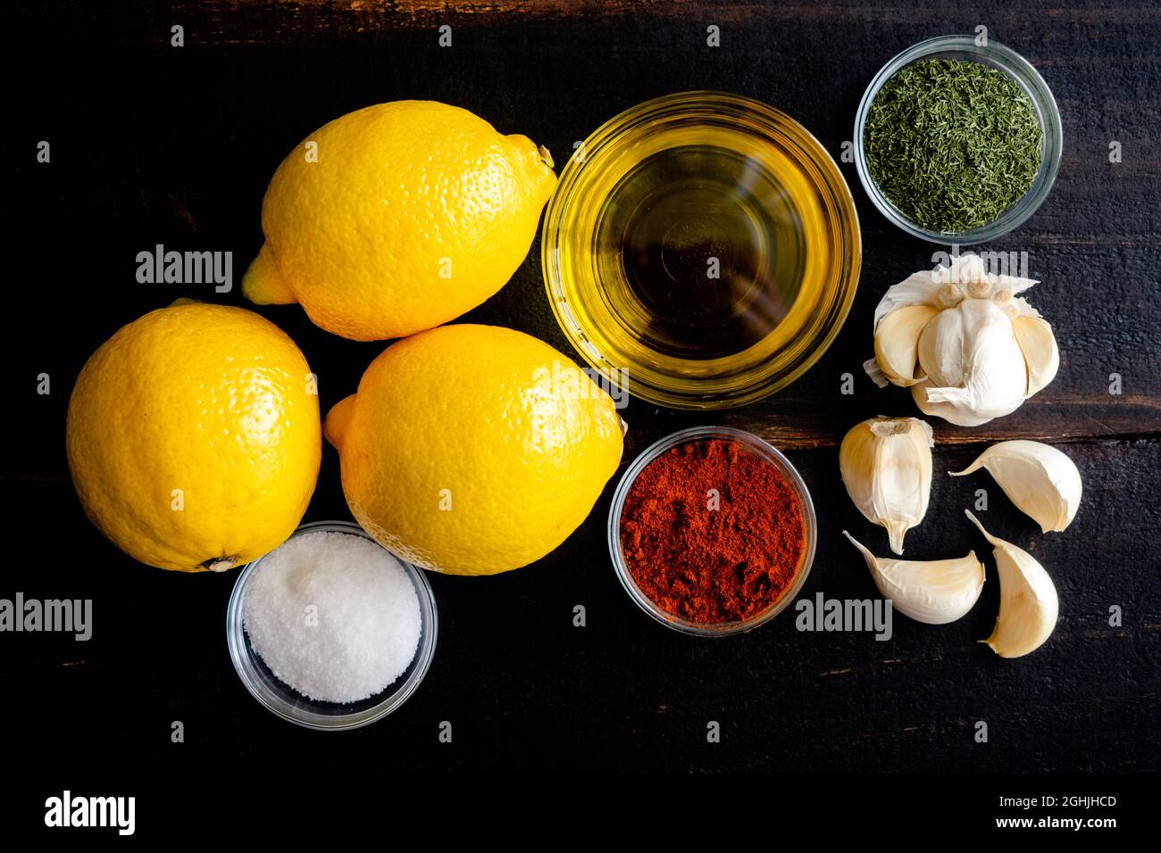 Lemon Garlic Marinade Ingredients on a Wood Table: Lemons, olive oil, and seasonings used to make a marinade Stock Photo