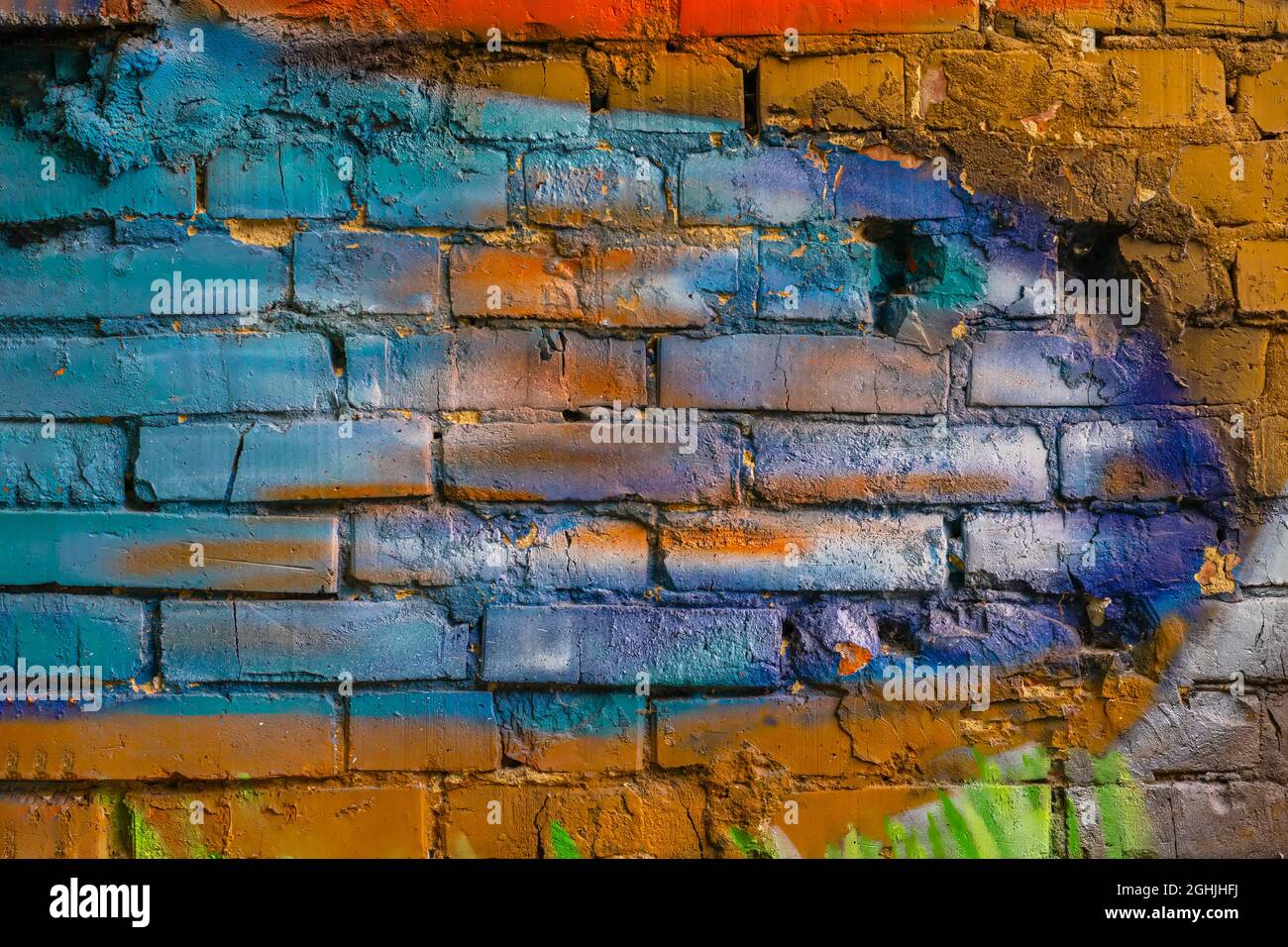 Rough plastered brick wall with cracks. Paint splash, colorful