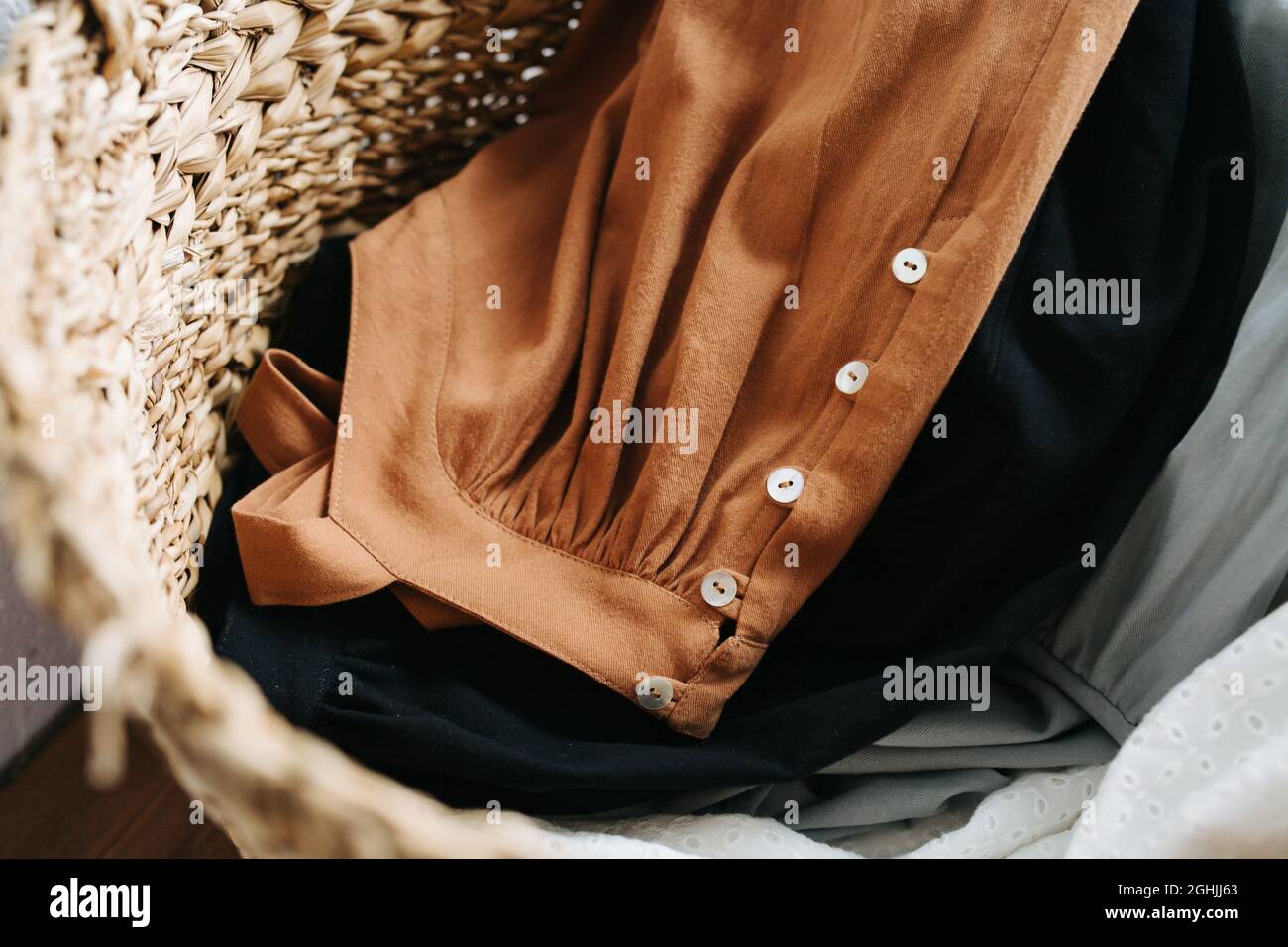 Close up image of a wicker basket full with summer dresses for washing laungry. Top view. Stock Photo