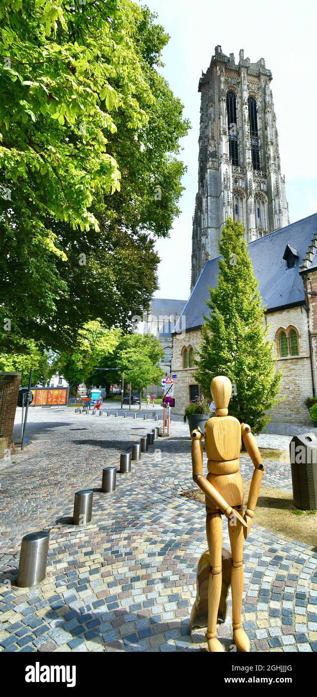 MECHELEN, BELGIUM - Aug 12, 2021: Magnificent photo of the gigantic tower of the cathedral of Saint Rumbold with in the foreground a wooden puppet of Stock Photo