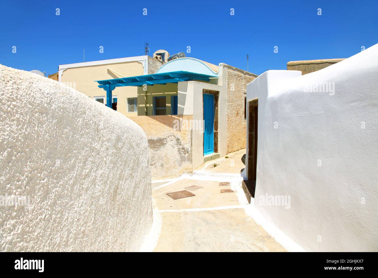 A small lane with white walls and a small house in the traditional village of Megalochori in Santorini, Greece. Stock Photo
