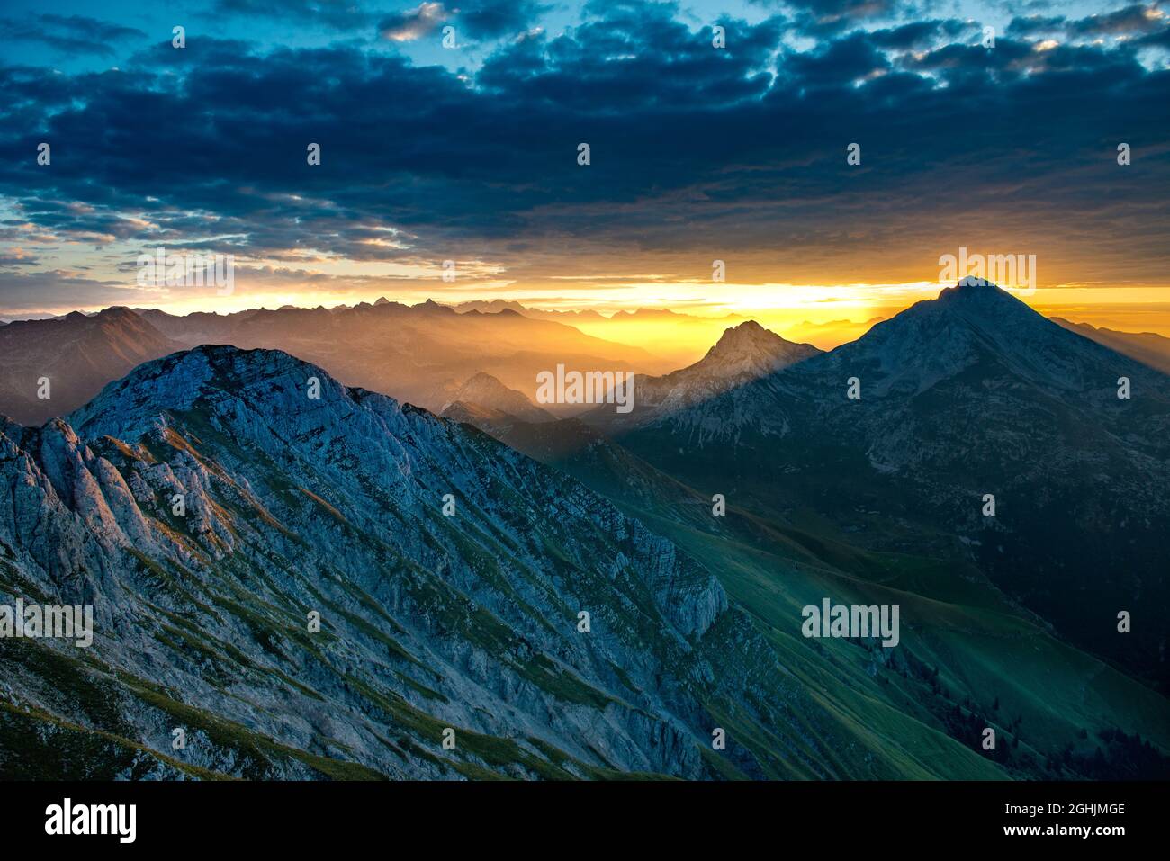 Sunrise in the mountains with the sun coloring the clouds Stock Photo ...
