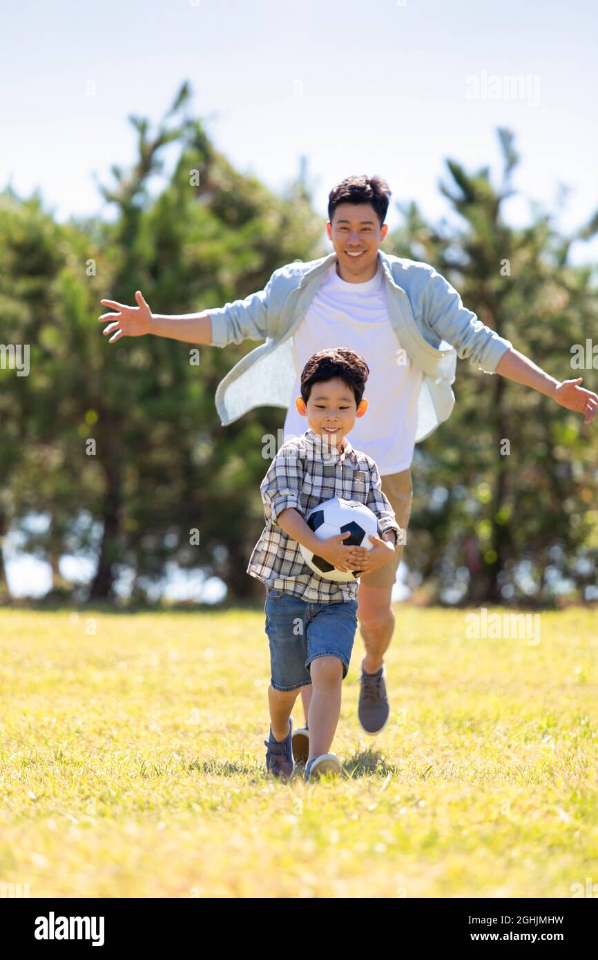 Happy father and son playing football in park Stock Photo - Alamy