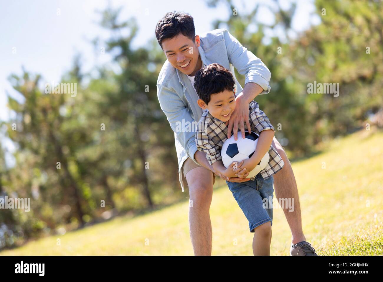 Happy father and son playing football in park Stock Photo - Alamy