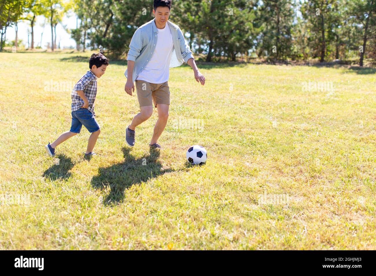 Happy father and son playing football in park Stock Photo - Alamy