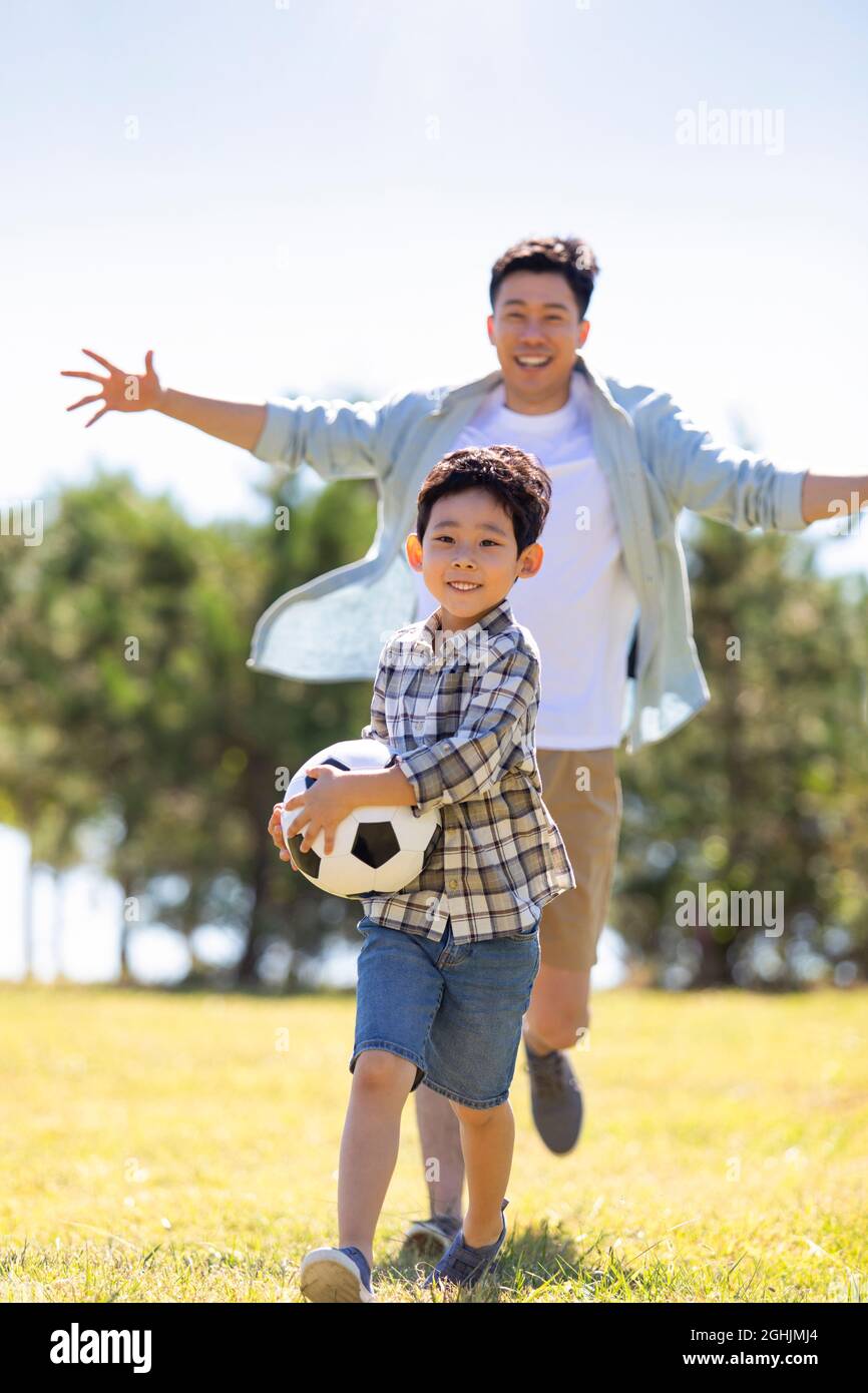 Happy father and son playing football in park Stock Photo - Alamy